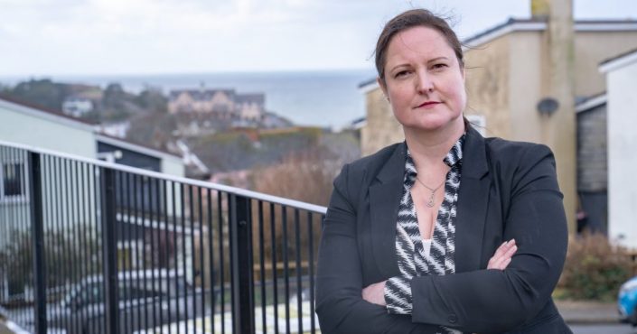 Police and Crime Commissioner Alison Hernandez standing with arms crossed by some railings in Ilfracombe with a view of the sea behind