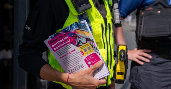 A Devon & Cornwall Police officer with a leaflet promoting the reporting of antisocial behaviour