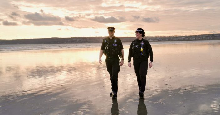Two police officers patrolling along a beach