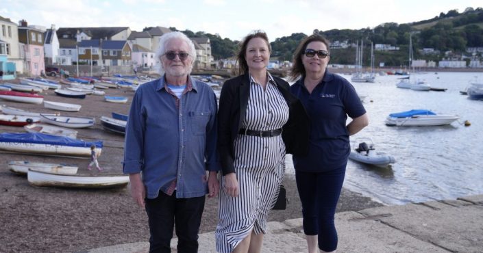 Commissioner Alison Hernandez stood against the backdrop of Teignmouth beach with Councillor Keith Underhill, left, and Jo Gask, owner of The Healthy Pet Shop, right